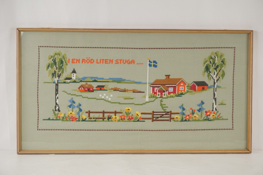 Handbroderat tavla I en röd liten stuga. M24/