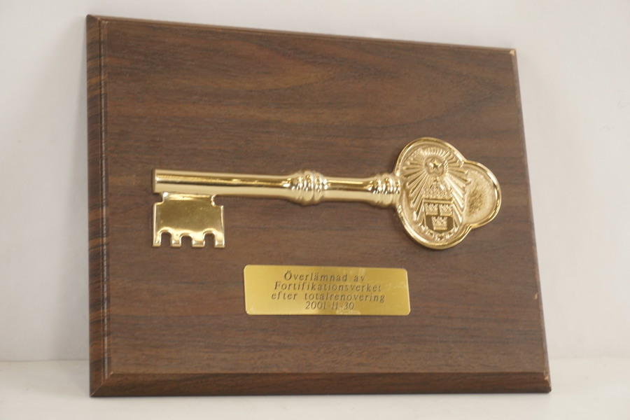 Ceremoniell nyckel monterad på en träplatta. A359