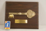 Ceremoniell nyckel monterad på en träplatta. A359